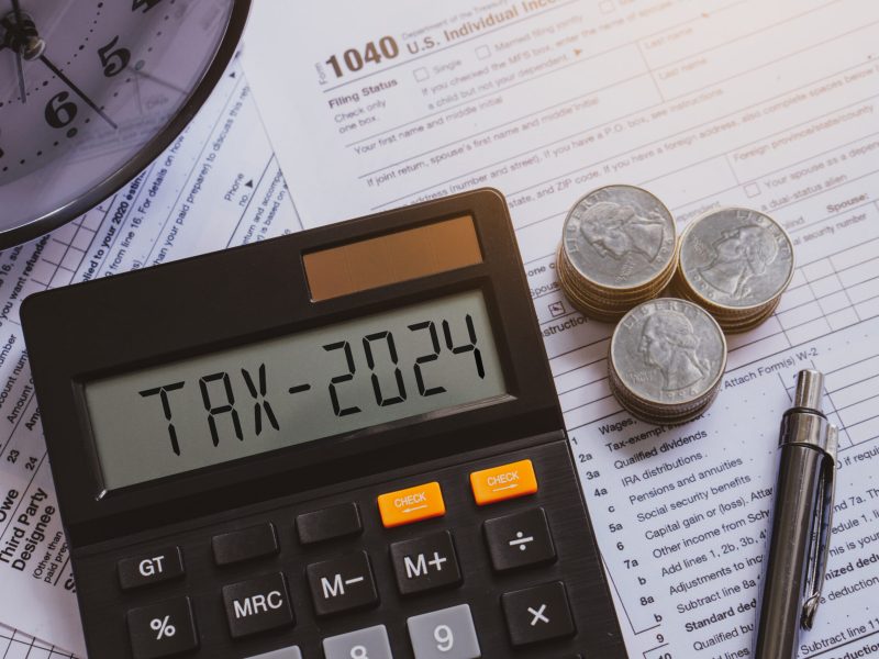 Tax 2024 word on calculator. Pay tax in 2024 years. The new year 2024 tax concept.Business and tax concept .Calculator, currency,tax from close up.